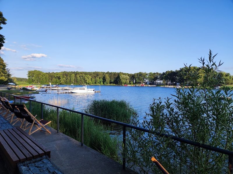 Jezioro i promenada na, której widać leżaki i ławki